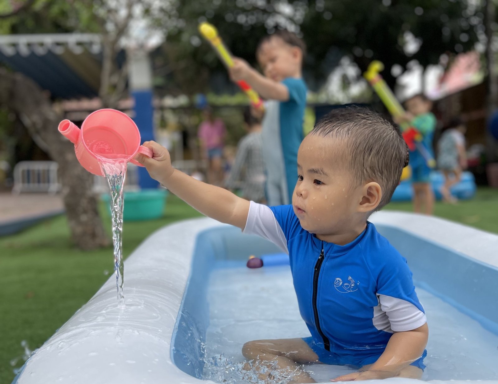 Un tout-petit joue avec l'eau à la crèche de Boule et Billes