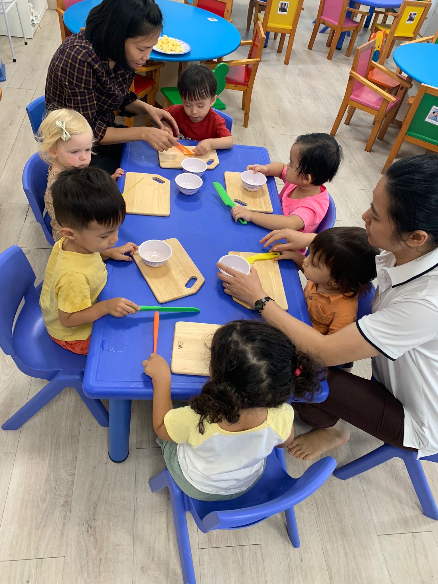 Các bé ở nhà trẻ cắt trái cây cùng các cô