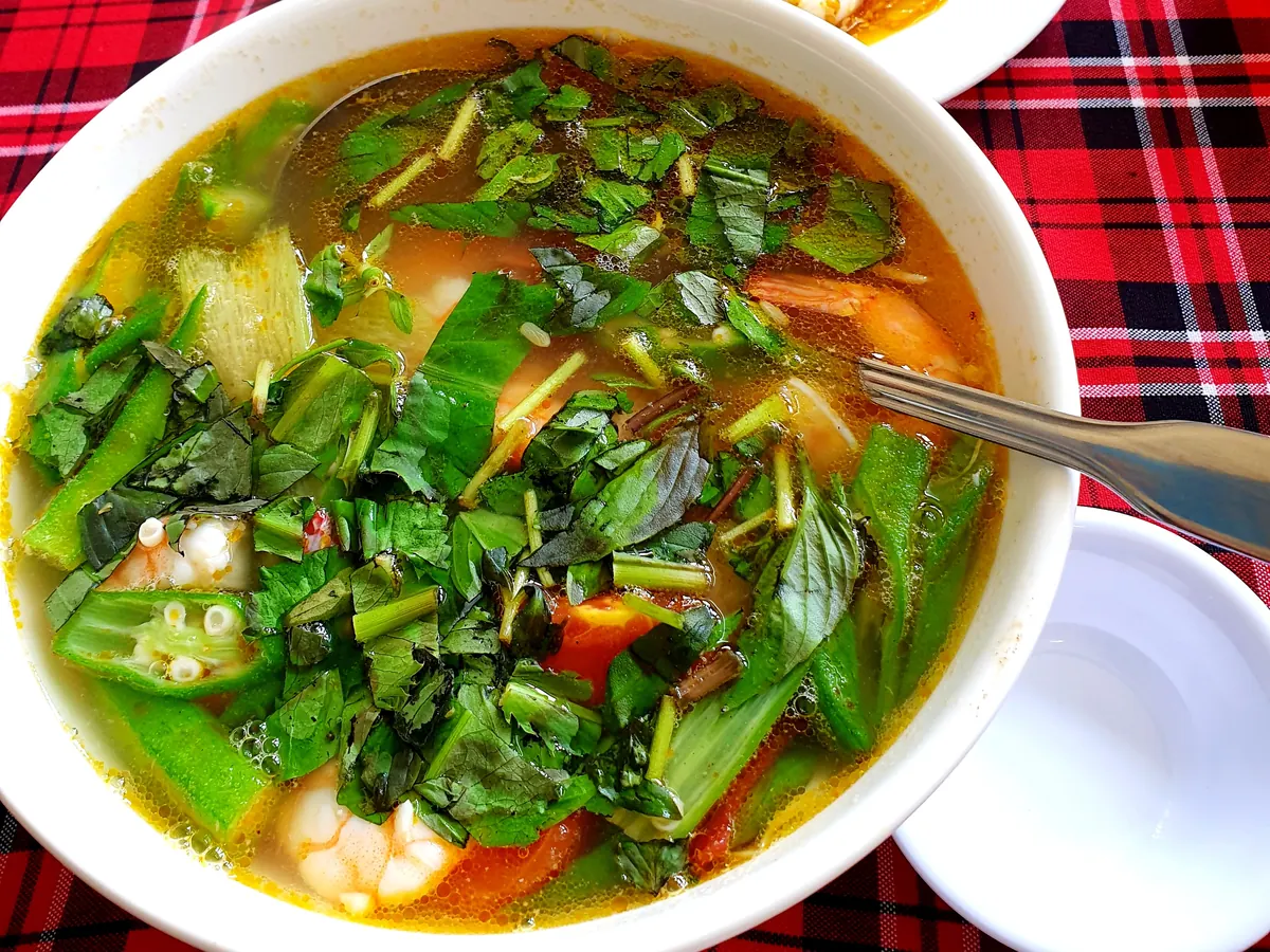 Un bol de canh chua aux crevettes, avec gombo, tomate et herbes fraîches