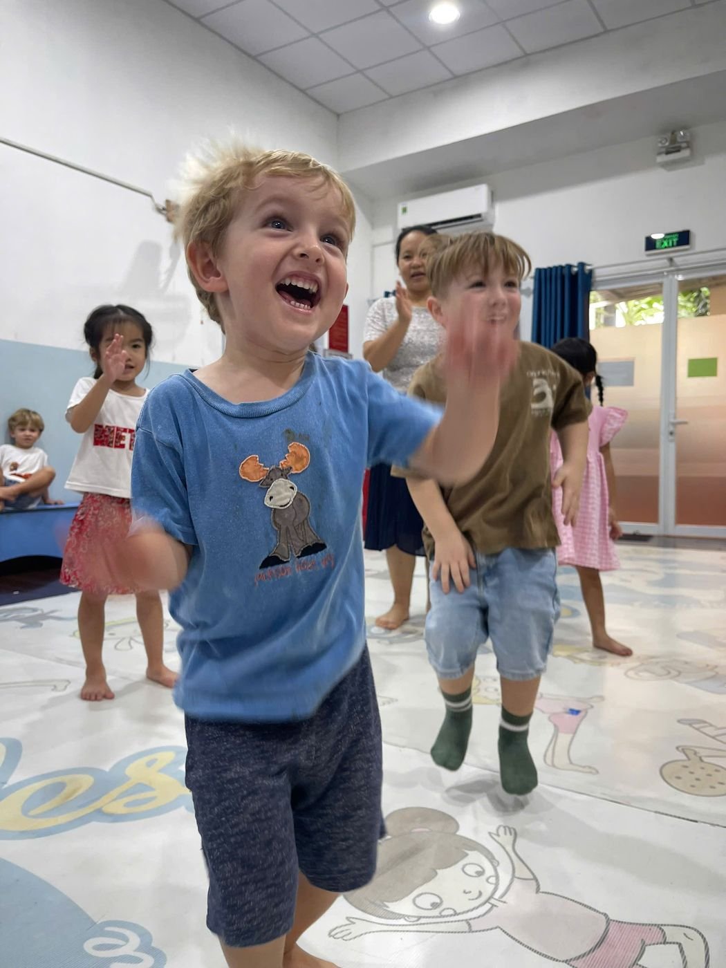 A little boy bursts out laughing while dancing with his friends
