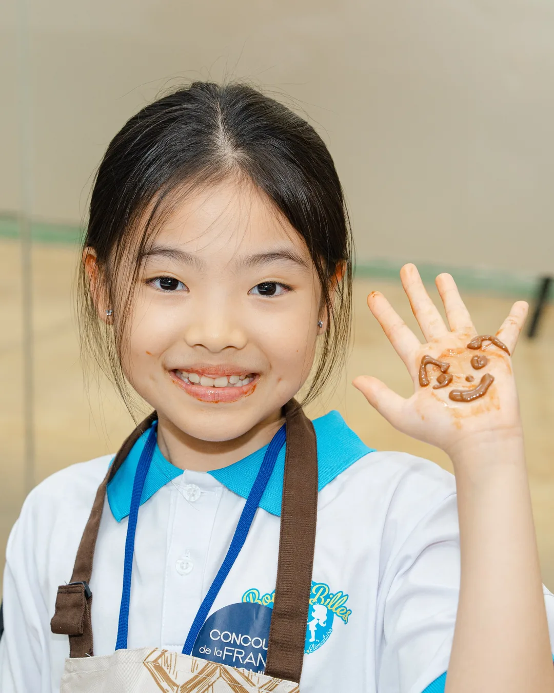 Une élève de CM1 montre en souriant sa main décorée d'un smiley en chocolat, aux Jeux francophones du Goût
