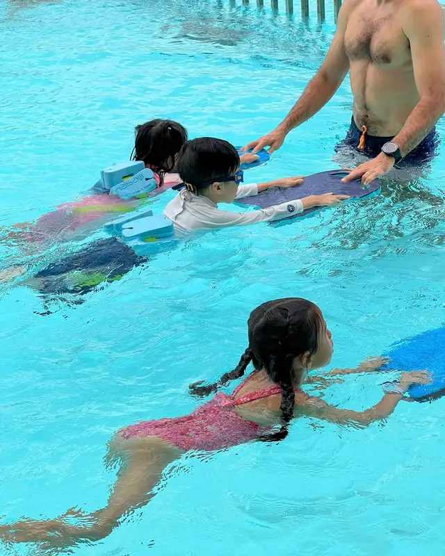 Enfants qui nagent avec une planche, guidés par leur maître-nageur, pendant l'activité natation de Boule et Billes