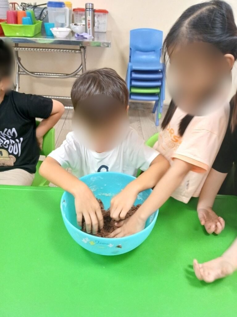 Two children knead chocolate dough in a mixing bowl