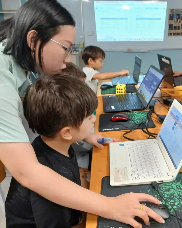 Enfant qui programme sur un ordinateur portable, aidé par son animatrice, pendant l'activité programmation de Boule et Billes