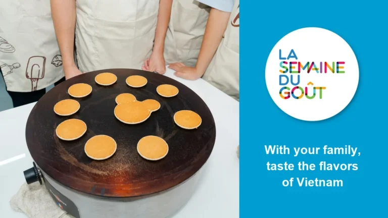 Crêpes cooking on a griddle at the Francophone Taste Games, one of them shaped like a mouse, next to the Semaine du goût logo and the words “With your family, taste the flavors of Vietnam”